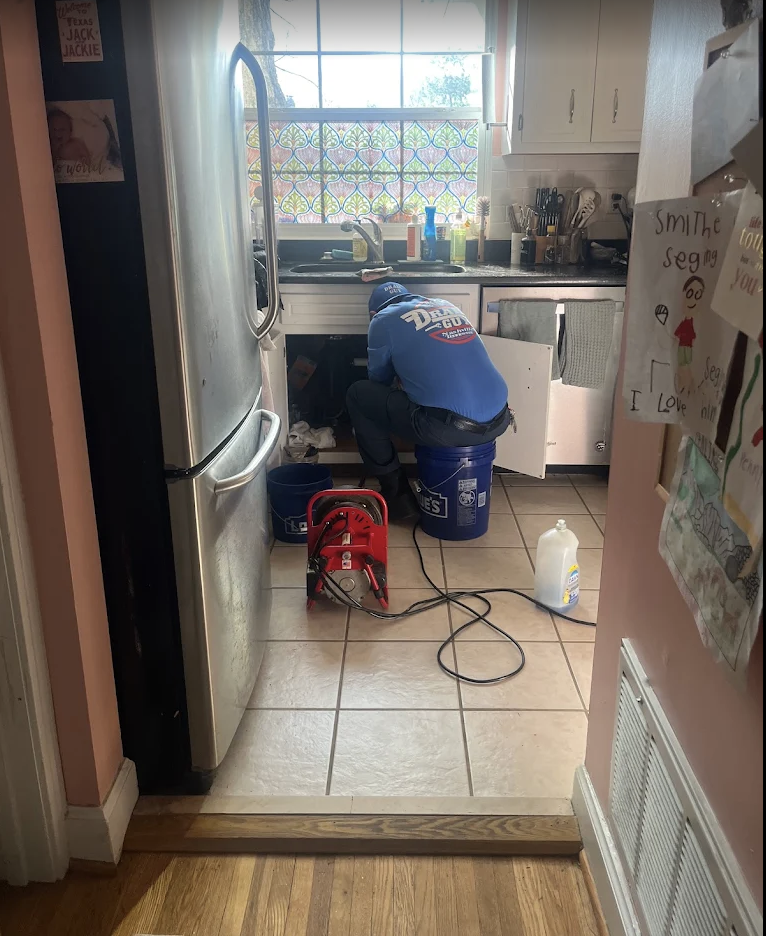 Drain Guy technician servicing a kitchen drain with professional equipment